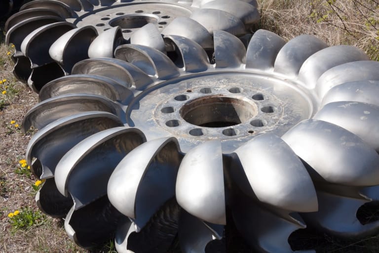 A stack of Pelton turbine rotors laid on an outdoor ground