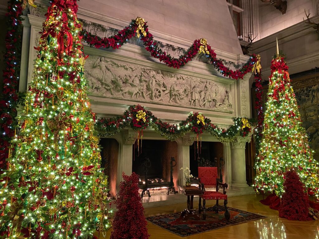 biltmore house fireplace surrounded by two christmas trees